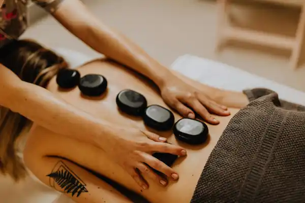 Entspannenden und entschleunigende Hot-Stone Massage auf einer Massageliege für die Beauty-Demo-Webiste